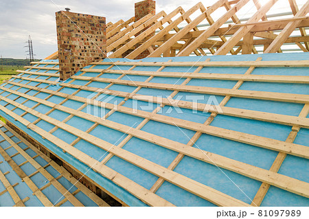 Aerial view of a brick house with wooden roof frame under construction. Aerial view of a brick house with wooden roof frame under construction. 81097989