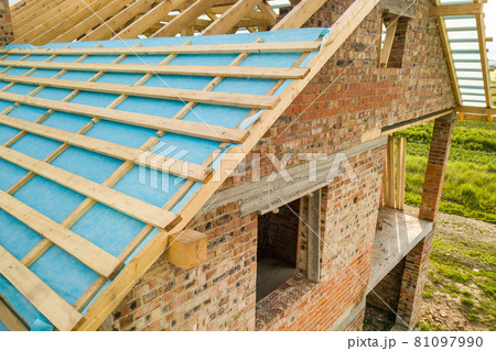 Aerial view of a brick house with wooden roof frame under construction. Aerial view of a brick house with wooden roof frame under construction. 81097990
