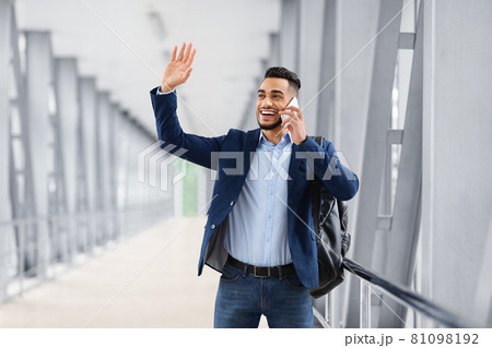 Arab Man Waving Hand And Talking On Cellphone While Walking In Airport Arab Man Waving Hand And Talking On Cellphone While Walking In Airport 81098192