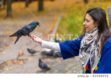 The person is holding a dove on the hand. Feeds pigeons in the park. Tame a pigeon 81098958