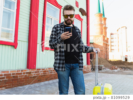 Portrait of happy travel man with suitcase standing near the building in city. 81099529