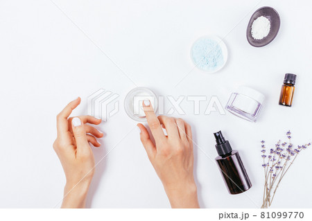 Female hands apply moisturizer next to lavender flowers Female hands apply moisturizer next to lavender flowers 81099770