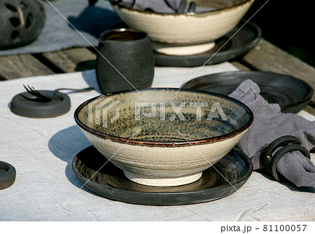 Rustic table setting outside in garden with empty craft ceramic tableware Rustic table setting outside in garden with empty craft ceramic tableware 81100057