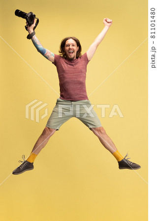 Portrait of young man, photographer, cameraman with camera isolated on yellow studio background. Concept of occupation, job, funny meme emotions Portrait of young man, photographer, cameraman with camera isolated on yellow studio background. Concept of occupation, job, funny meme emotions 81101480
