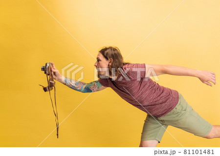 Portrait of young man, photographer, cameraman with retro camera isolated on yellow studio background. Concept of occupation, job, funny meme emotions Portrait of young man, photographer, cameraman with retro camera isolated on yellow studio background. Concept of occupation, job, funny meme emotions 81101481