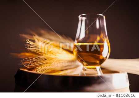 A glass of whiskey on oak barrel A glass of whiskey on oak barrel 81103616