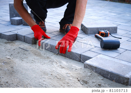 The master in yellow gloves lays paving stones The master in yellow gloves lays paving stones 81103713