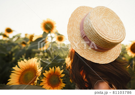 Young woman having a walk in sunflowers field in the morning 81103786