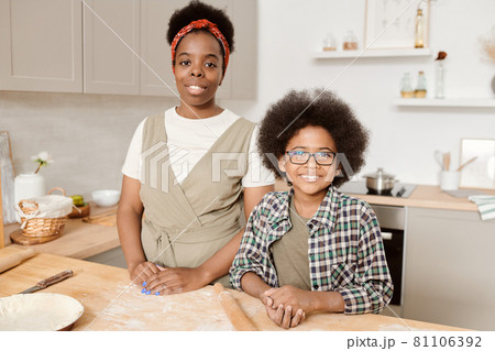 Happy mother and son standing by kitchen table 81106392