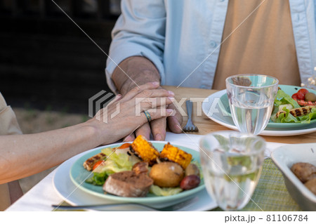 Hands of mature affectionate couple sitting by served table by dinner Hands of mature affectionate couple sitting by served table by dinner 81106784