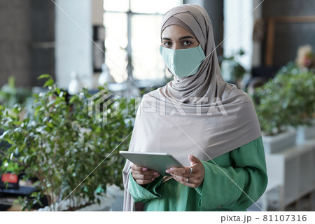 Young Muslim businesswoman with tablet looking at camera Young Muslim businesswoman with tablet looking at camera 81107316