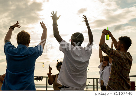 Joyful friends with beer raising arms while dancing 81107446