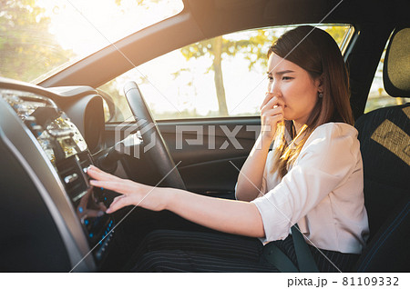 Young Asian woman holding her nose because of bad smell after turn on car air conditioning 81109332