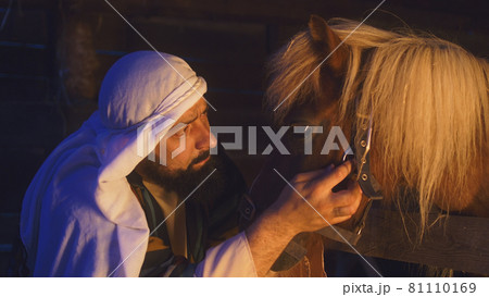 Joseph petting horse in dark barn 81110169