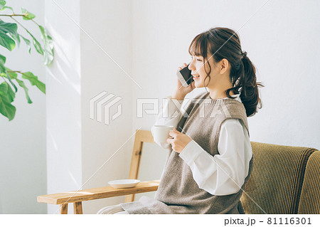 リビングで電話をする若い女性 リビングで電話をする若い女性 81116301