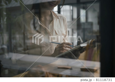 View through window of businesswoman holding pen and making note on notebook. View through window of businesswoman holding pen and making note on notebook. 81118731