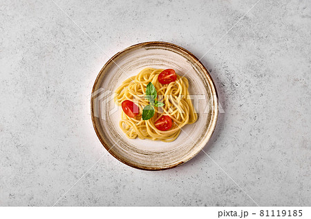 Top view spaghetti with tomato cherry, parmesan cheese and basil on ceramic plate 81119185