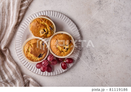 Flat lay homemade cupcakes with cherries and grapes on plate with napkin 81119186