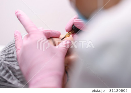 Permanent makeup artist makes eye arrows for client closeup 81120605