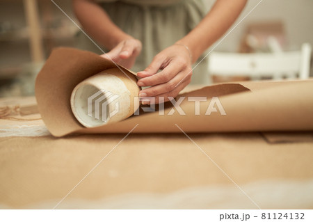 Crop woman wrapping clay cup in craft paper Crop woman wrapping clay cup in craft paper 81124132