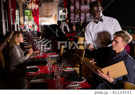 African-american waiter is taking order from client in fashionable restaurant African-american waiter is taking order from client in fashionable restaurant 81124541