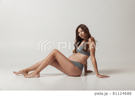 Portrait of sensual pregnant woman in lingerie isolated over grey studio background. Natural beauty, happy motherhood, femininity concept. 81124686
