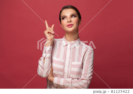 Cute brunette woman pointing up on red background banner 81125422