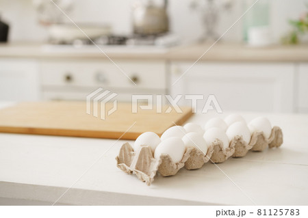 Eggs in egg box on white wooden table in kitchen 81125783