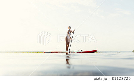 One young Caucasian beautiful slim girl sunbathe on summer evening on river on paddle board, SUP alone. Active life, sport, leisure activity concept One young Caucasian beautiful slim girl sunbathe on summer evening on river on paddle board, SUP alone. Active life, sport, leisure activity concept 81128729