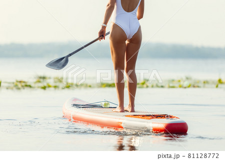 One young Caucasian beautiful slim girl sunbathe on summer evening on river on paddle board, SUP alone. Active life, sport, leisure activity concept 81128772