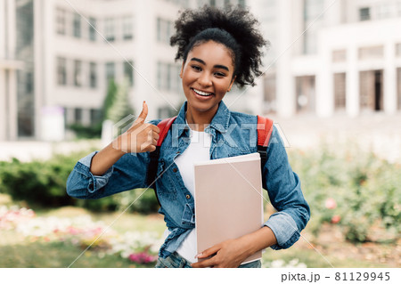 African American Female Student Gesturing Thumbs-Up Posing Near University Building 81129945