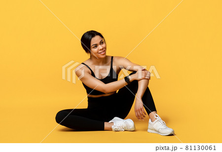 Fitness and sport concept. Fit african american woman resting after workout, sitting on floor at yellow background 81130061