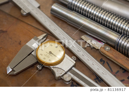 Close up scene of dial vernier caliper and the machine parts on the work bench. Close up scene of dial vernier caliper and the machine parts on the work bench. 81136917