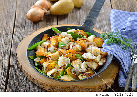 Fried potatoes with pieces of halibut fillet, sugar peas and onion rings, served in a frying pan Fried potatoes with pieces of halibut fillet, sugar peas and onion rings, served in a frying pan 81137629