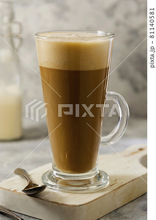 Coffee drink with whipped milk in tall glass cup with cinnamon. 81140581