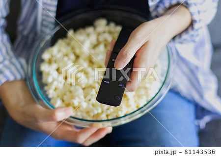 ポップコーンを片手にリモコン操作する女性 81143536