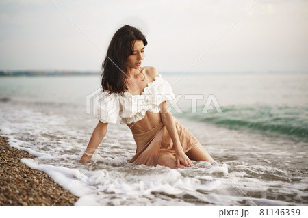 Young relaxed woman sitting all alone on empty beach 81146359