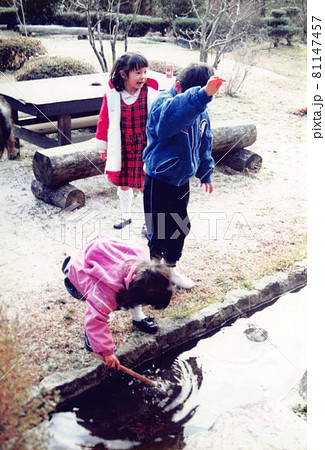 昔のフィルム写真　池で遊ぶ三人のきょうだい 81147457