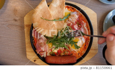 Eating Shakshuka Poached Eggs with Tomato and Bread Served in a Frying Pan. Israeli Arab Middle Eastern Cuisine. 4k. Top view Eating Shakshuka Poached Eggs with Tomato and Bread Served in a Frying Pan. Israeli Arab Middle Eastern Cuisine. 4k. Top view 81150661