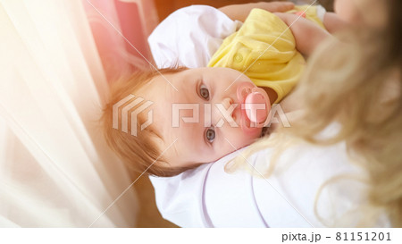 Young mother wearing white shirt soothes worried baby girl 81151201