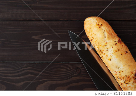 Baguette bread on brown wooden board close up 81151202
