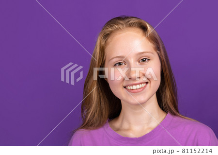 Half-length portrait of young beautiful smiling girl isolated on purple studio background. Concept of human emotions, facial expression, youth, sales, ad. Half-length portrait of young beautiful smiling girl isolated on purple studio background. Concept of human emotions, facial expression, youth, sales, ad. 81152214