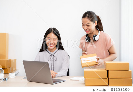 Asian woman business two people owner with many parcel boxes on the table happy online sales job, use your laptop, get an order from customers, take notes, and make arrangements for delivery by post 81153100