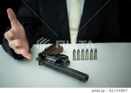 Unrecognizable businessman put the revolver hand gun on the table. Unrecognizable businessman put the revolver hand gun on the table. 81154807