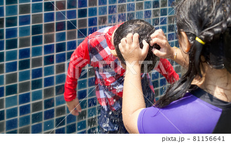 The older sister help her younger brother wash salt water out of his hair after playing in the swimming pool. The older sister help her younger brother wash salt water out of his hair after playing in the swimming pool. 81156641
