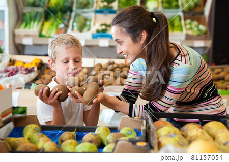 Portrait of happy woman and her little son choosing kiwi at shop Portrait of happy woman and her little son choosing kiwi at shop 81157054