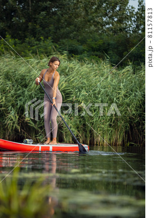 Young Caucasian woman, sportsman, tourist standing on paddle board, SUP, practicing alone. Active life, sport, leisure activity concept 81157813