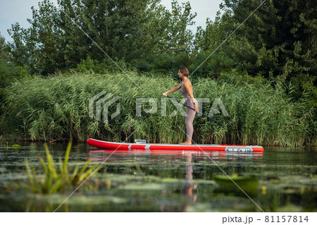 Young Caucasian woman, sportsman, tourist standing on paddle board, SUP, practicing alone. Active life, sport, leisure activity concept Young Caucasian woman, sportsman, tourist standing on paddle board, SUP, practicing alone. Active life, sport, leisure activity concept 81157814