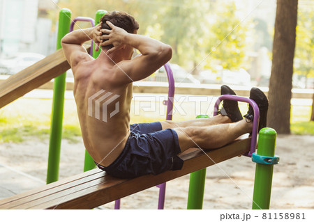 One young handsome caucasian man in sportswear training, exercising on sports ground outdoors on bright summer day. One young handsome caucasian man in sportswear training, exercising on sports ground outdoors on bright summer day. 81158981