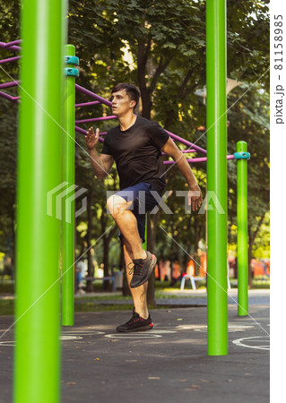 One young handsome caucasian man in sportswear training, exercising on sports ground outdoors on bright summer day. 81158985